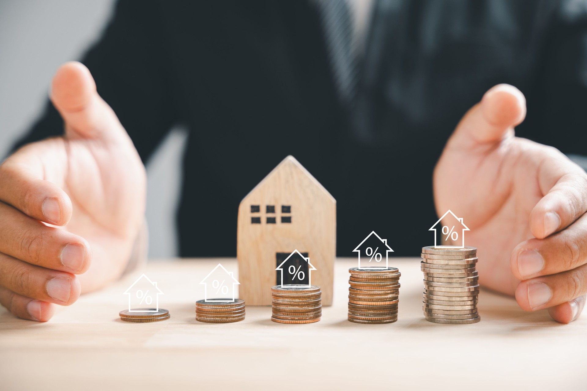 Businessman with house wooden and coin stack, real estate profit plan